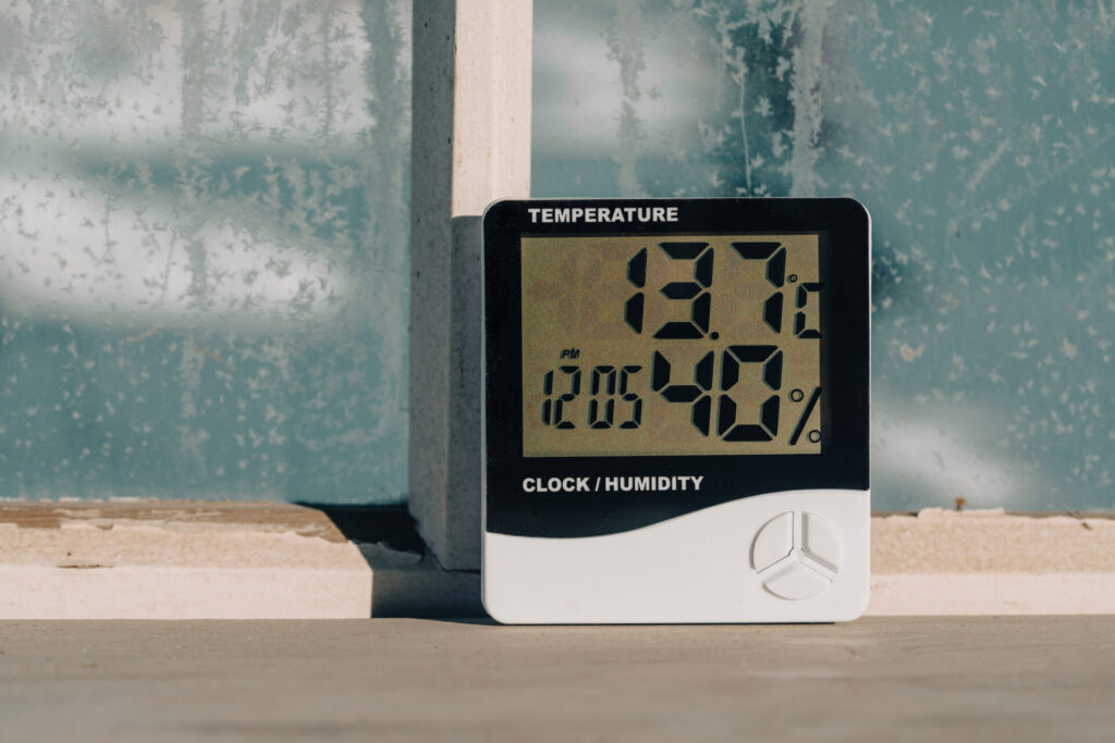 Electronic device to check temperature and humidity in closed area near window in winter sunny day, close up